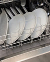A dishwasher of clean white plates