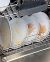 A dishwasher loaded with dirty white plates