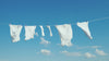 White laundry hanging on a clothesline against a clear blue sky with clouds