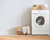 A washing machine next to a laundry basket