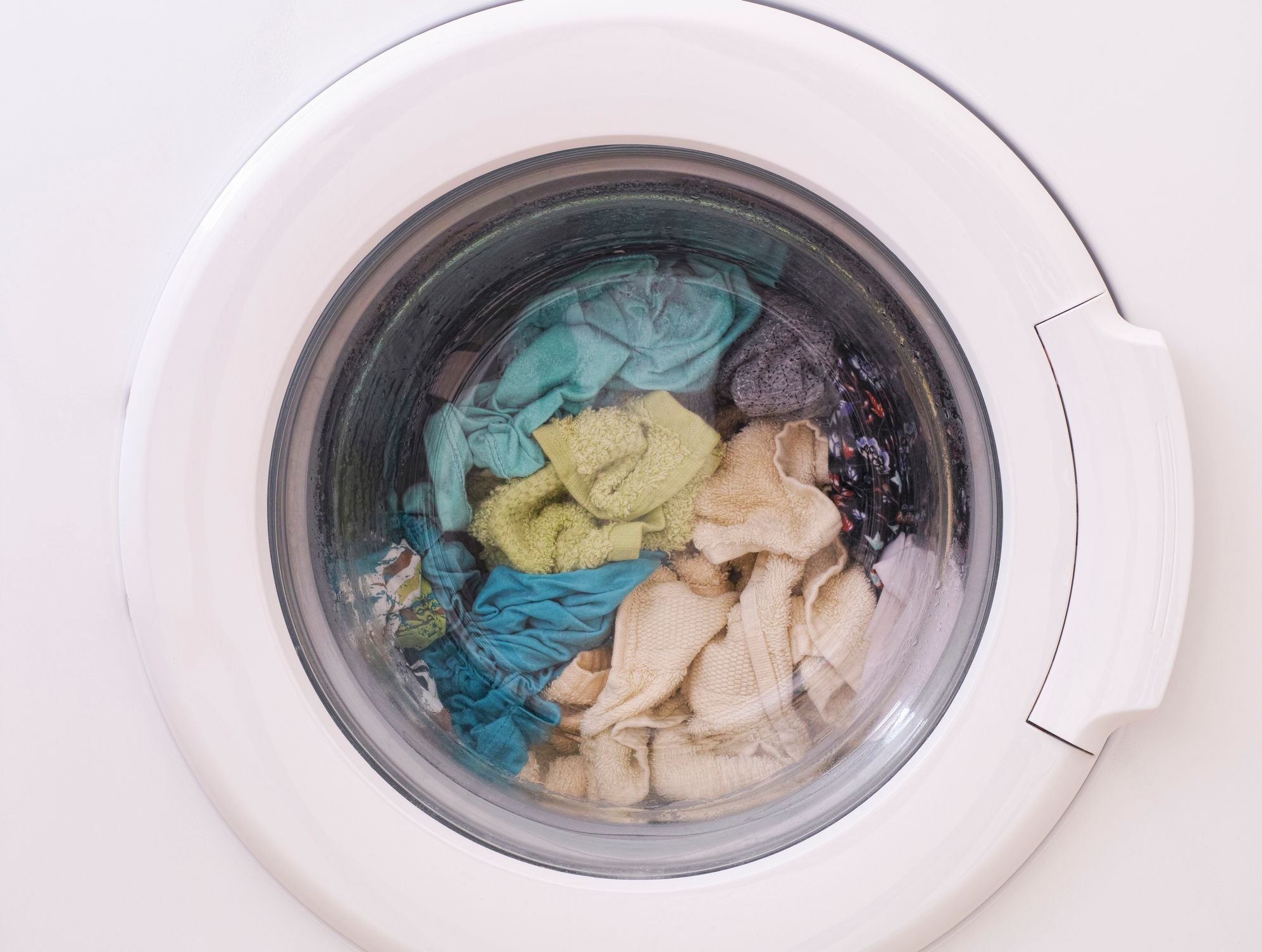 Washing machine with clothes inside on a white background