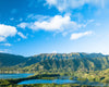 Blue sky over green grass covered mountains and lake