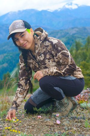 Person in camouflage jacket and cap in a mountainous landscape
