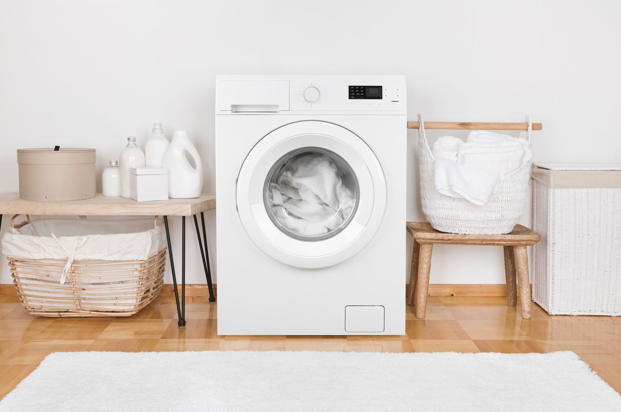 White washing machine in a laundry room with wooden floor and shelves.