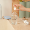 A hand adding a hand soap refill tablet to a hand soap bottle